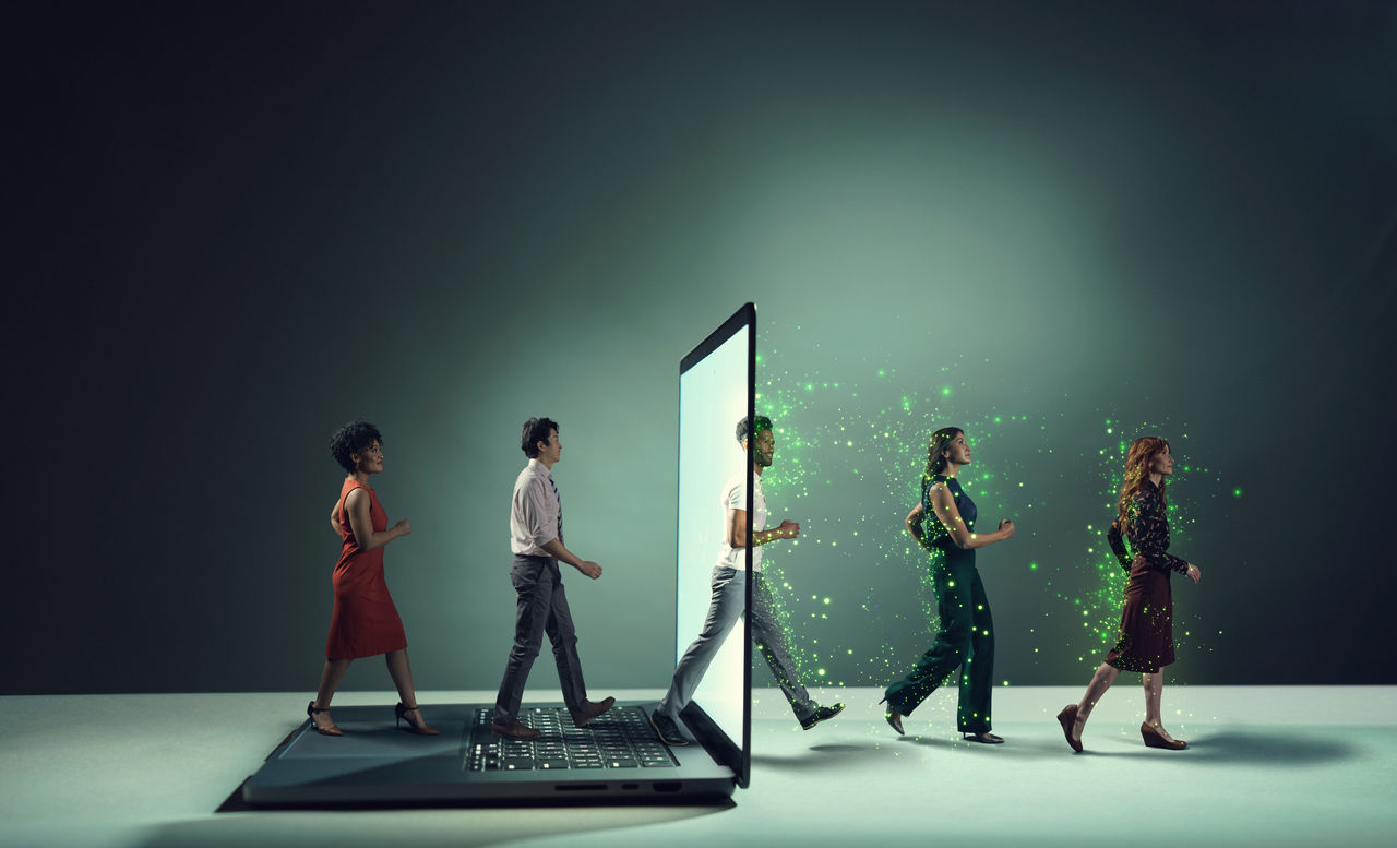 تصویری از افرادی که از درون یک لپتاپ خارج میشوند، نشانهای از تأثیر فناوری و هوش مصنوعی بر زندگی و کار انسانها. ذرات درخشان اطراف آنها نمایانگر نوآوری و پتانسیلهای جدید است.